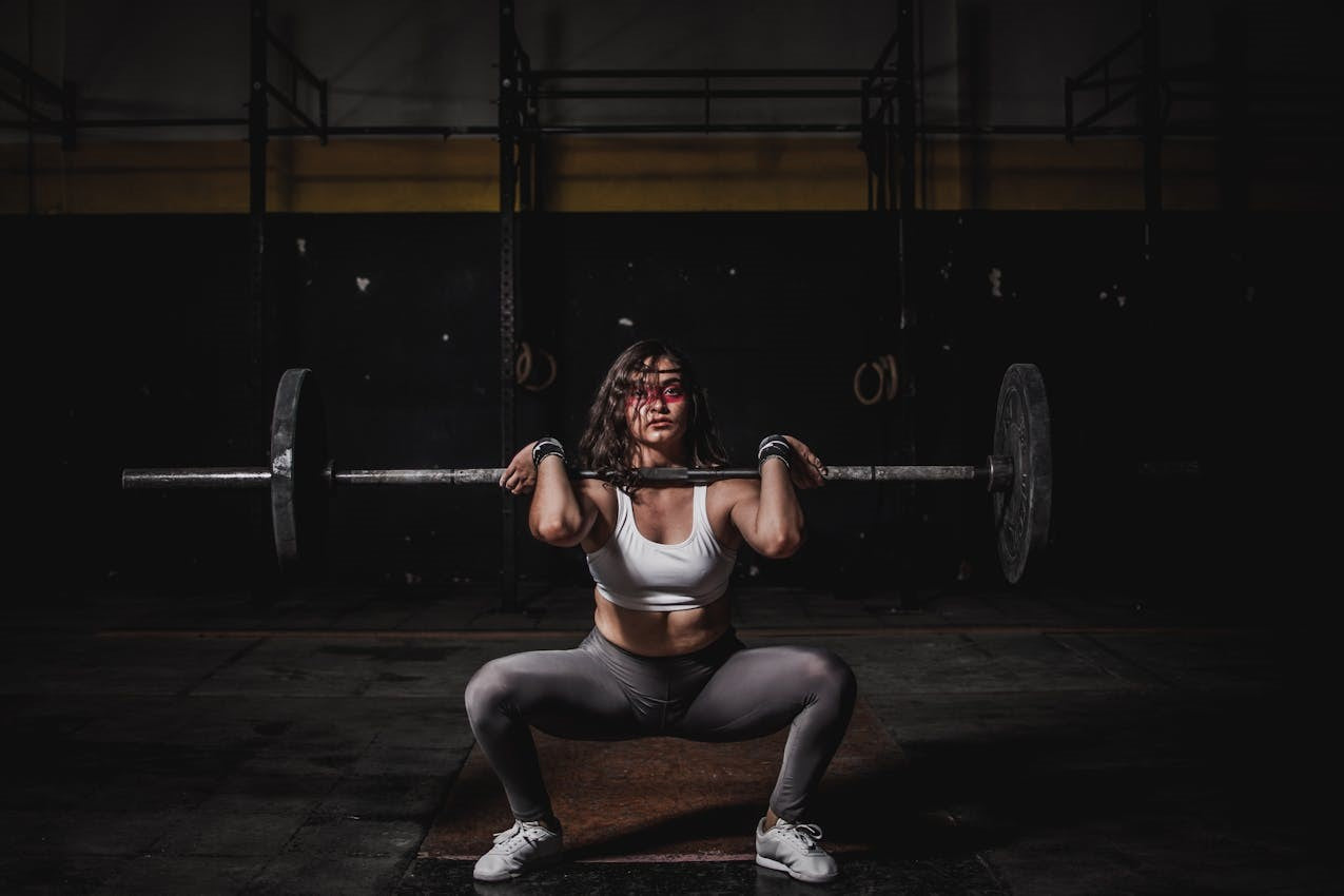 A woman in a sports bra performing a heavy barbell front squat in a gym.