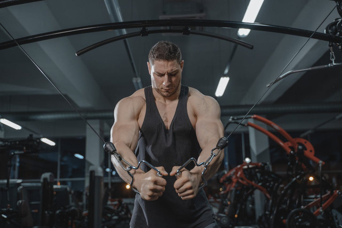Bodybuilder working out on a cable machine, focusing on strength training in the gym.