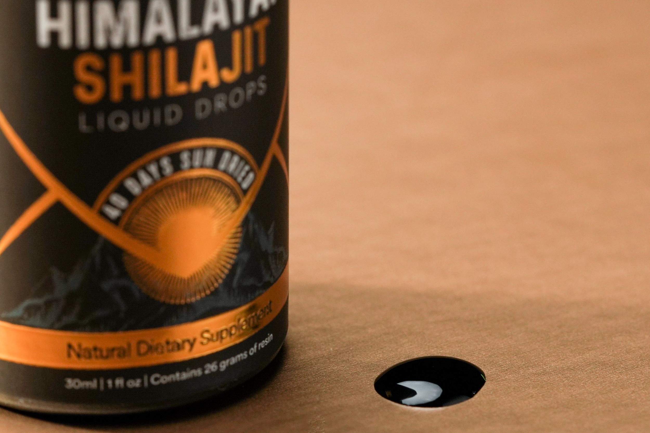 Bottle of Himalayan Shilajit Liquid Drops with a small amount of black resin liquid spilled on a surface.