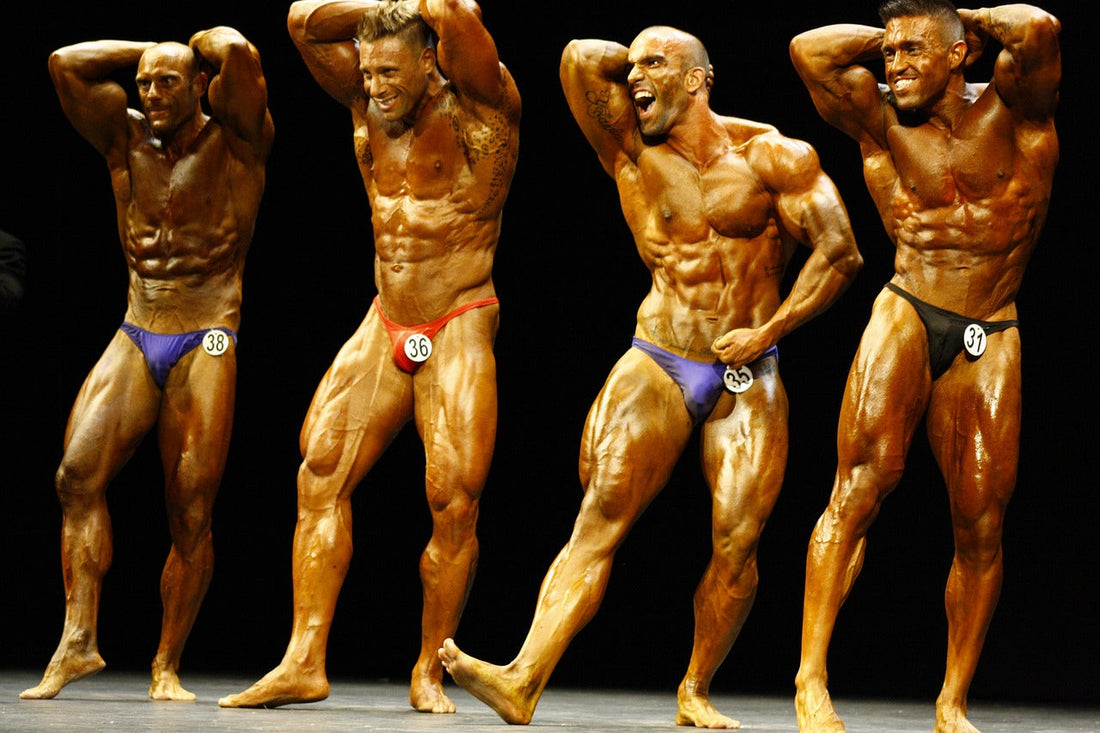 Four male bodybuilders flexing their muscles on stage during a bodybuilding competition.