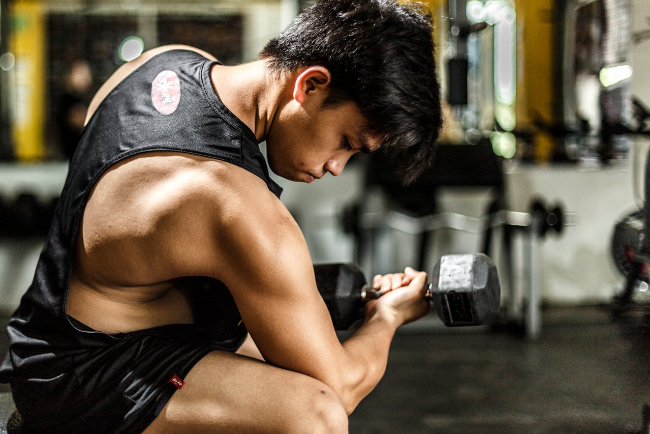 Man focusing intensely while lifting a dumbbell in a gym setting.