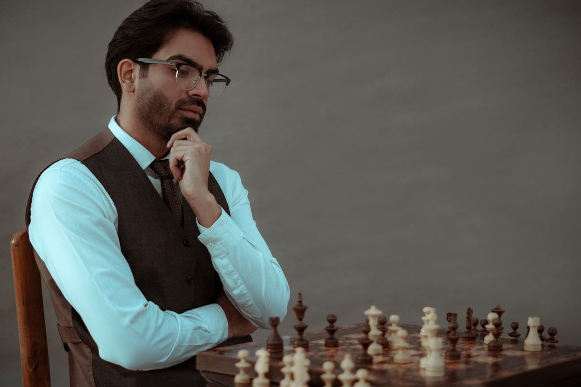 Man thoughtfully playing chess in formal attire, contemplating his next move.