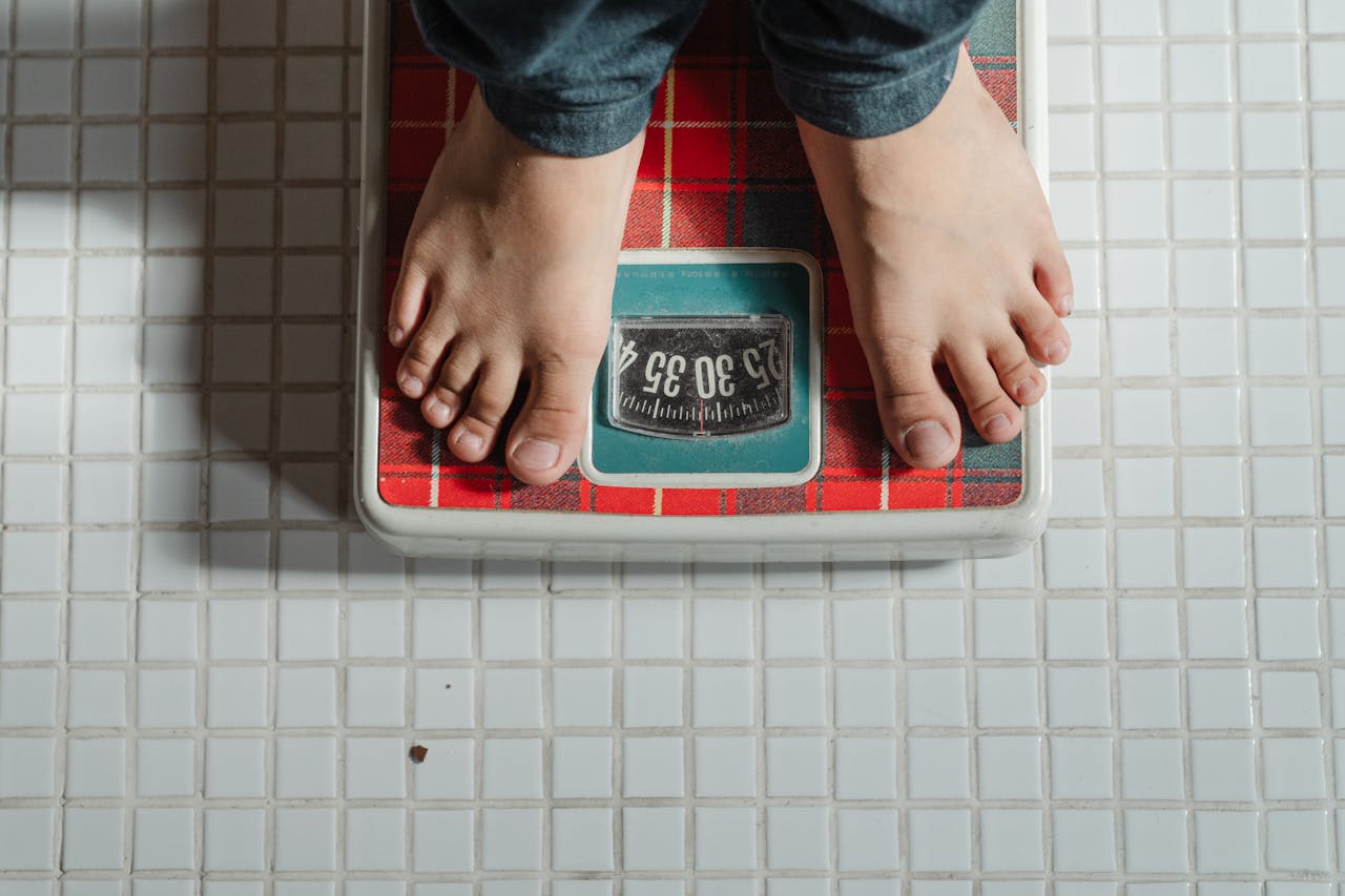Person standing on a bathroom scale, checking their weight.