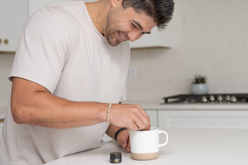Man smiling as he dissolves Shilajit resin into a mug of warm milk.