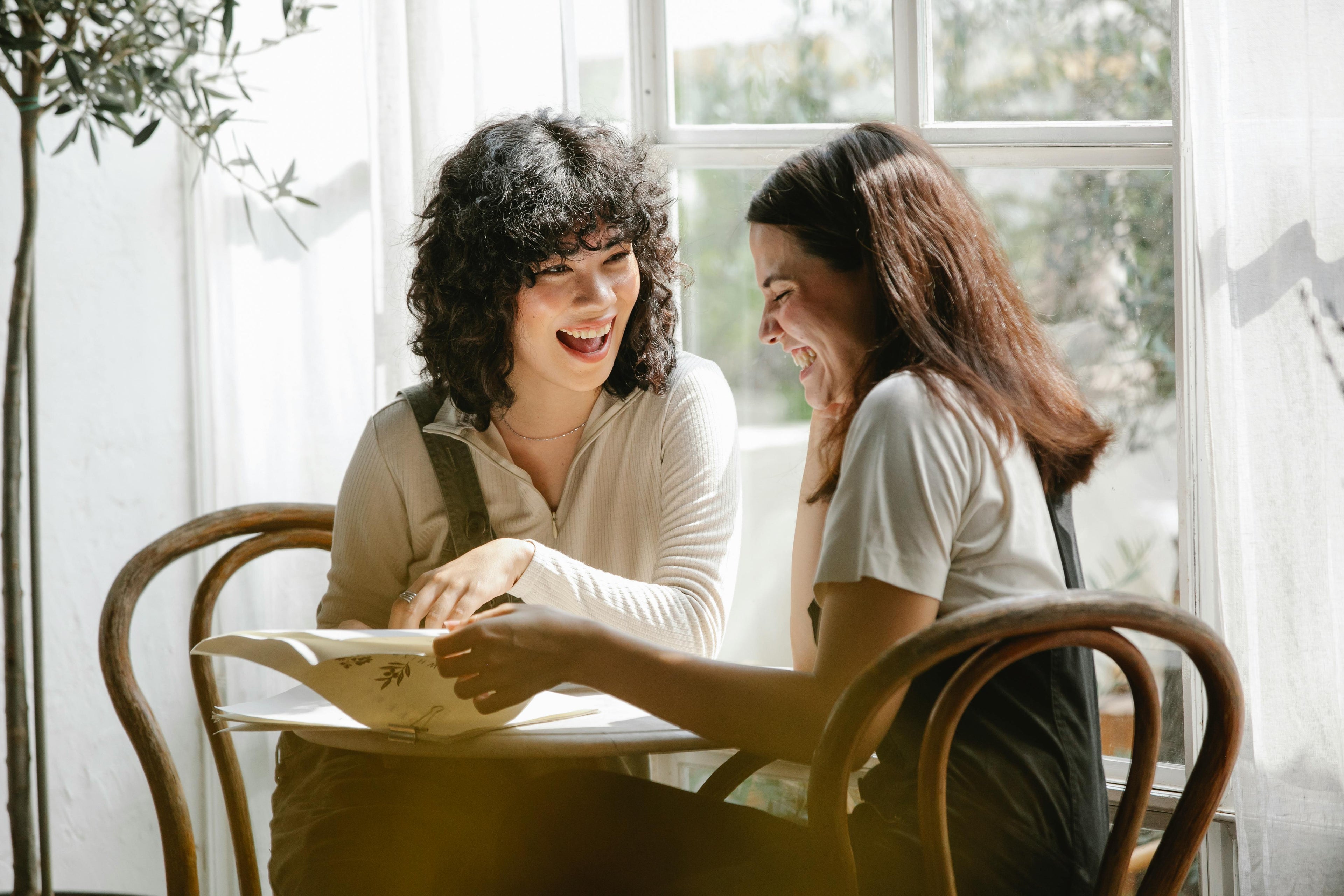 Two women laughing and enjoying a conversation at a cafe.