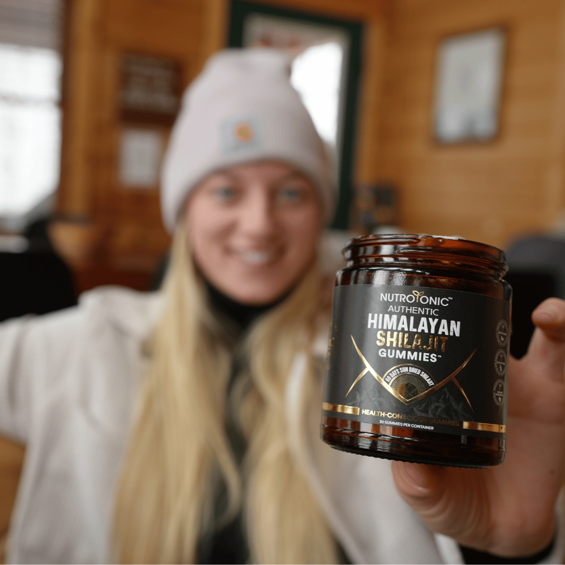 Woman holding a jar of NutroTonic Himalayan Shilajit Gummies glass jar
